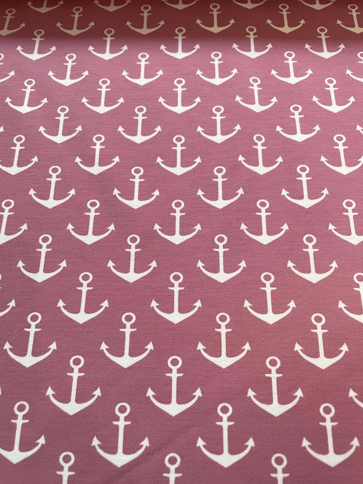 French Terry Stoff in Altrosa mit weißem Allover-Anker-Print, Detailaufnahme der Stoffstruktur.
