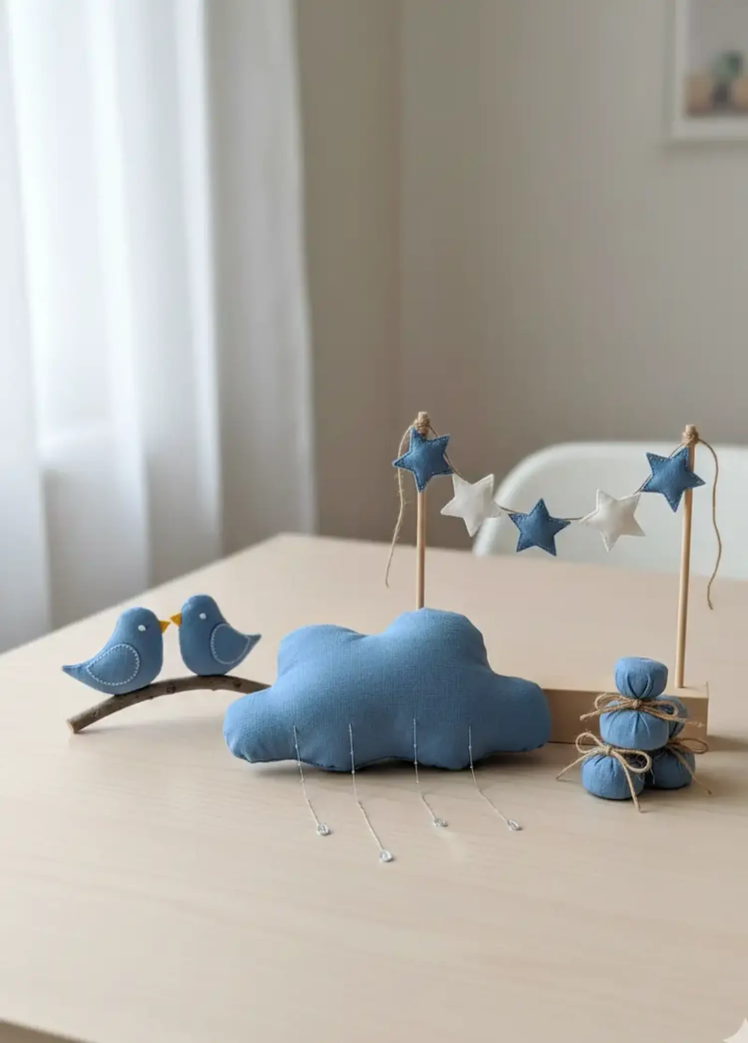 Anwendungsbeispiel für mittelblauen Baumwollstoff als Meterware: Eine genähte blaue Wolke mit Regentropfen, kleine Vögelchen auf einem Ast und eine Sterngirlande als Dekoration fürs Kinderzimmer.