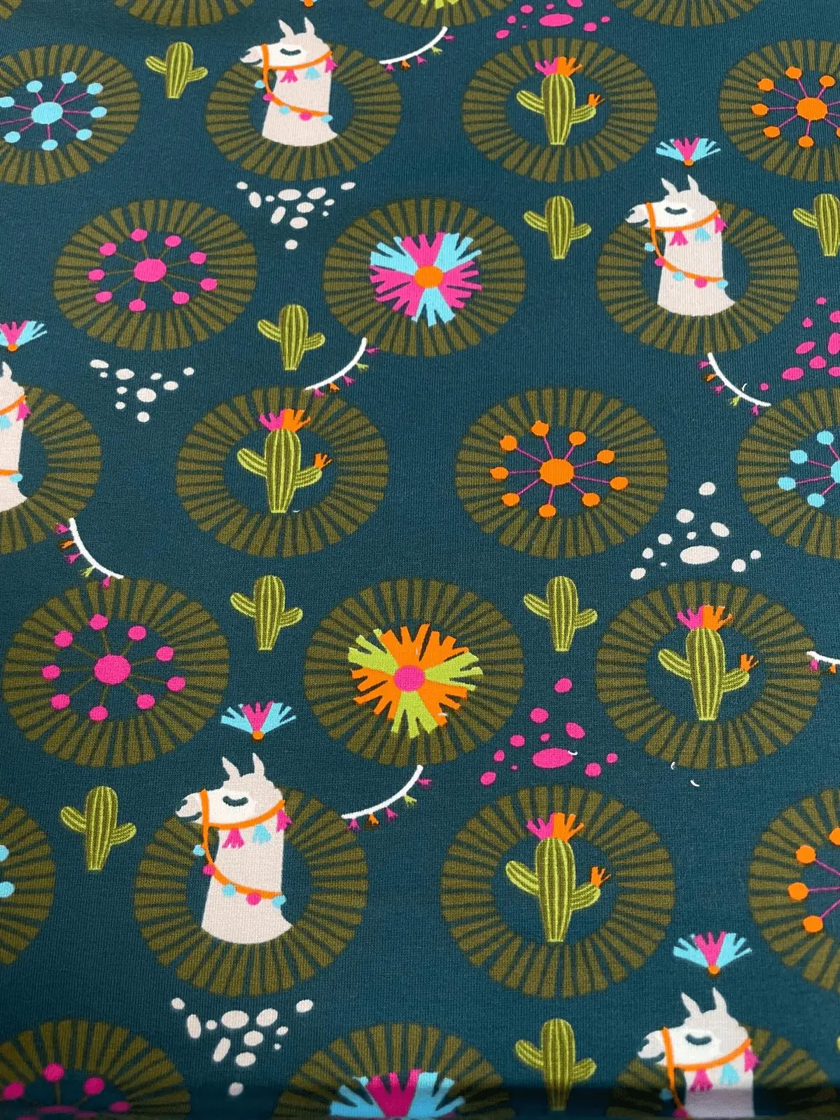 Petrolfarbener French Terry Sweatstoff als Meterware mit bunten Lama- Motiven, Kakteen und Ethno-Mustern, ideal für Kinderkleidung und Hoodies.