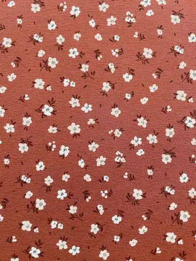 Weicher Jerseystoff in Rostbraun mit zierlichem weißen Blumenmuster, ideal für Kinderkleidung und Damenmode
