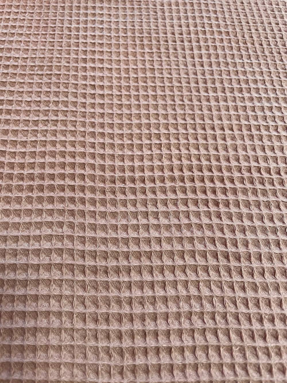 Nahaufnahme von braunem Waffelpique Stoff als Meterware mit charakteristischer Waffelstruktur für Decken, Handtücher und herbstliche DIY-Projekte.