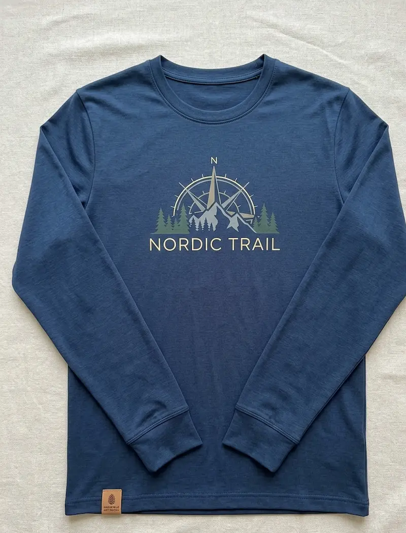 Dunkelblaues Longsleeve aus Baumwolljersey Uni Navy mit Nordic Trail Kompass-Print und Berg-Motiv auf hellem Hintergrund.