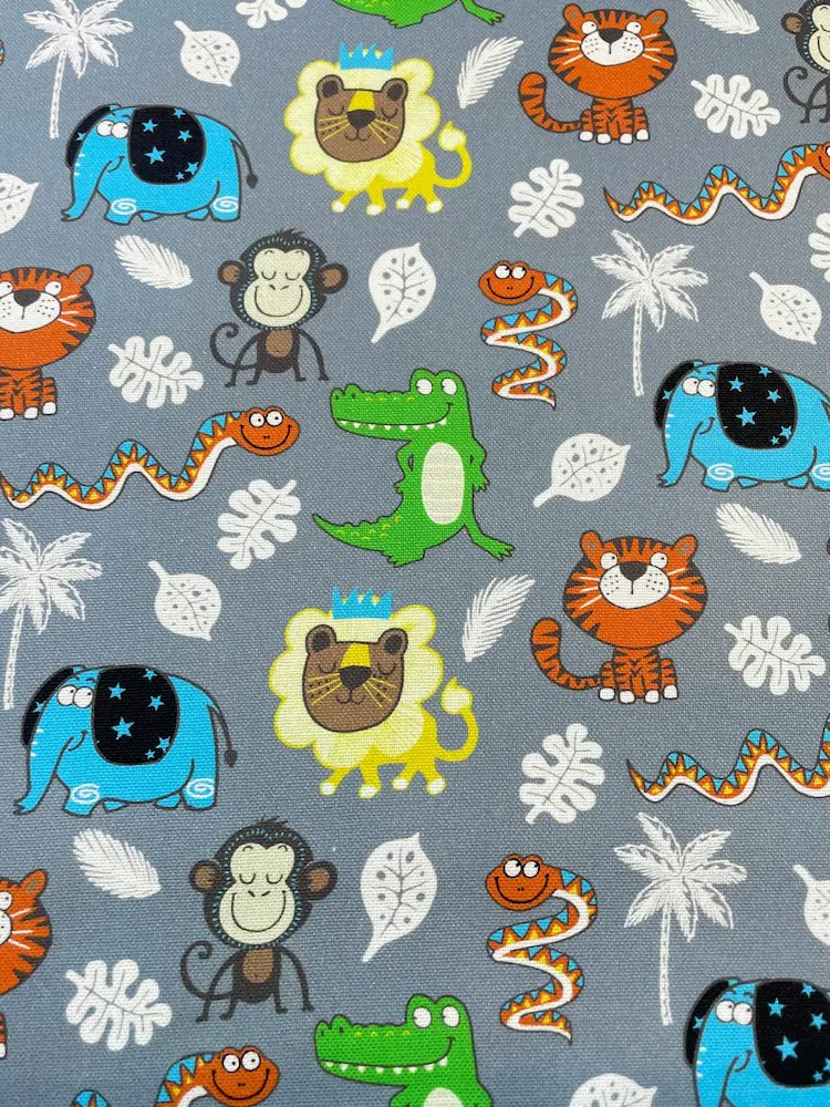 Süßer Kinder-Dekostoff als Meterware in Grau mit bunten Dschungeltieren wie Löwe, Elefant, Tiger, Affe und Krokodil.