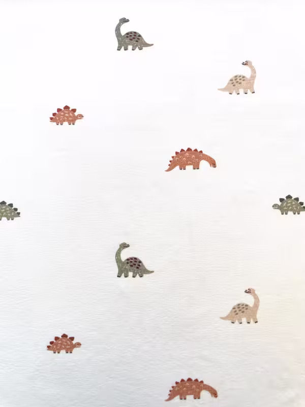 Weicher Baumwolljersey in Cremeweiß bedruckt mit kleinen Dinosauriern in Braun und Salbeigrün für Kinderkleidung.