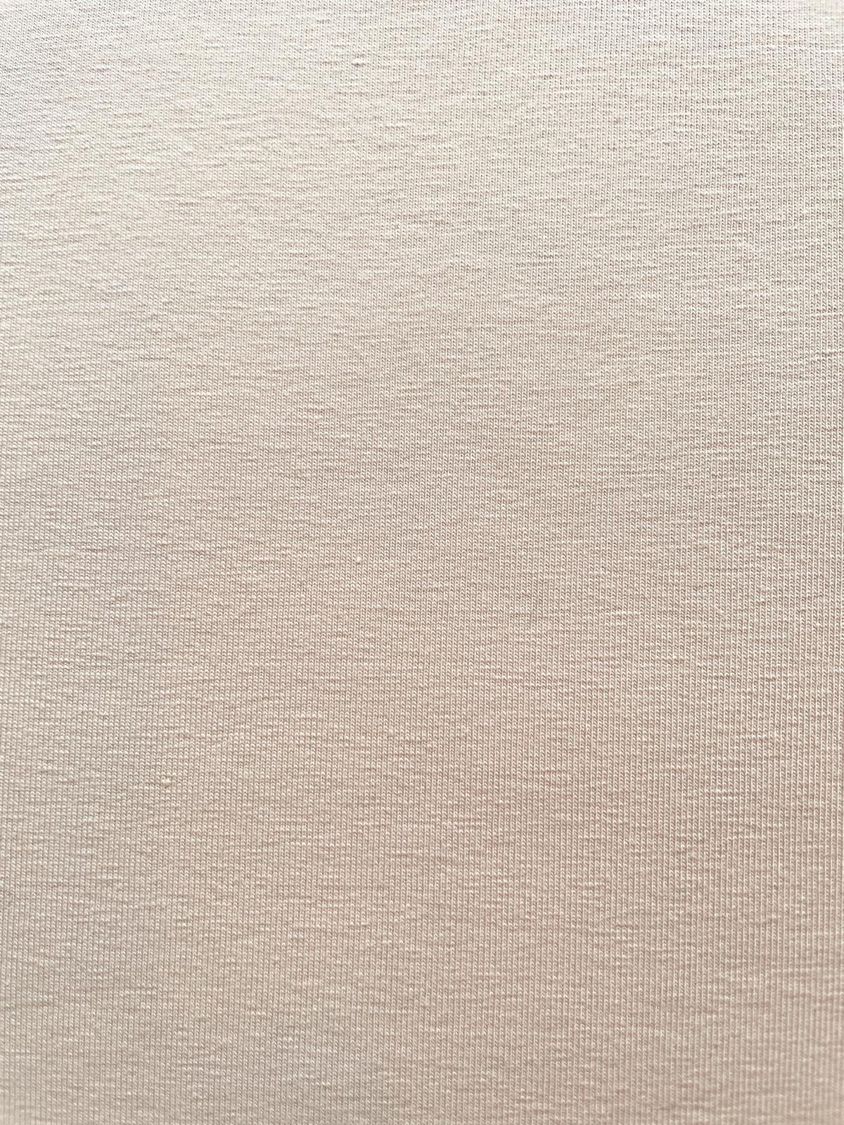 Nahaufnahme von hellem, unbehandeltem Jersey-Stoff aus 95% Baumwolle und 5% Elasthan mit weichem Faltenwurf.