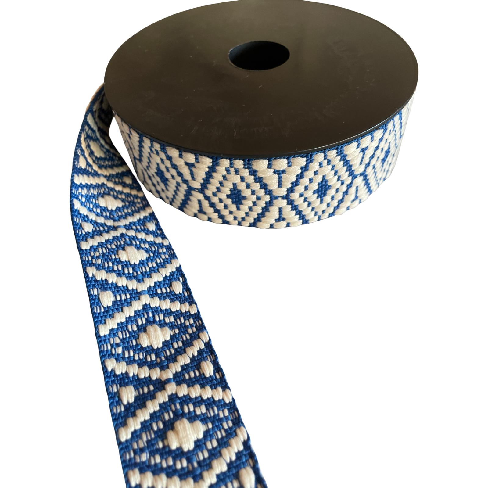 Stabiles Gurtband auf einer Rolle als Meterware in Blau und Weiß mit einem eingewebten geometrischen Ethno-Muster.