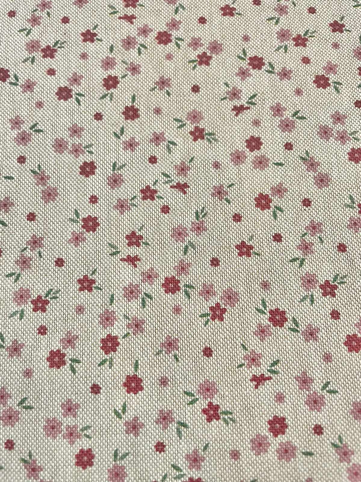Strukturierter Dekostoff als Meterware mit kleinen, zarten Streublümchen in Rosa und Rot auf hellem Hintergrund in Leinenoptik.