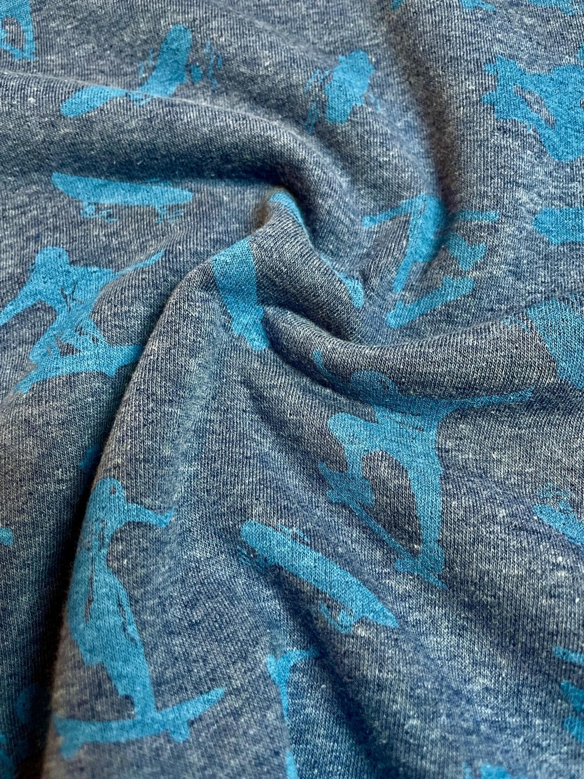 Warmer Alpenfleece Stoff in Jeansblau Melange mit türkisen Skater-Motiven, weich gefütterter Kuschelsweat für Kinder, Meterware.
