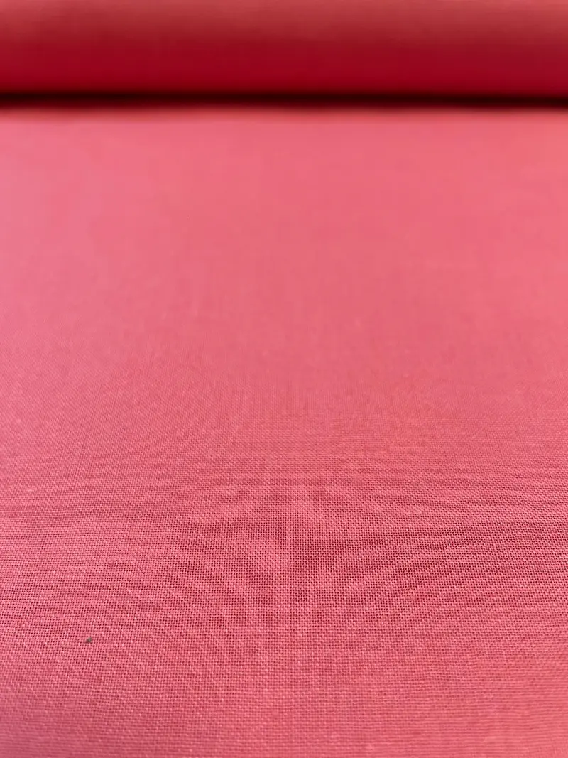 Fein gewebter Uni-Baumwollstoff in Coral beziehungsweise Lachsrosa als Meterware aus nächster Nähe.