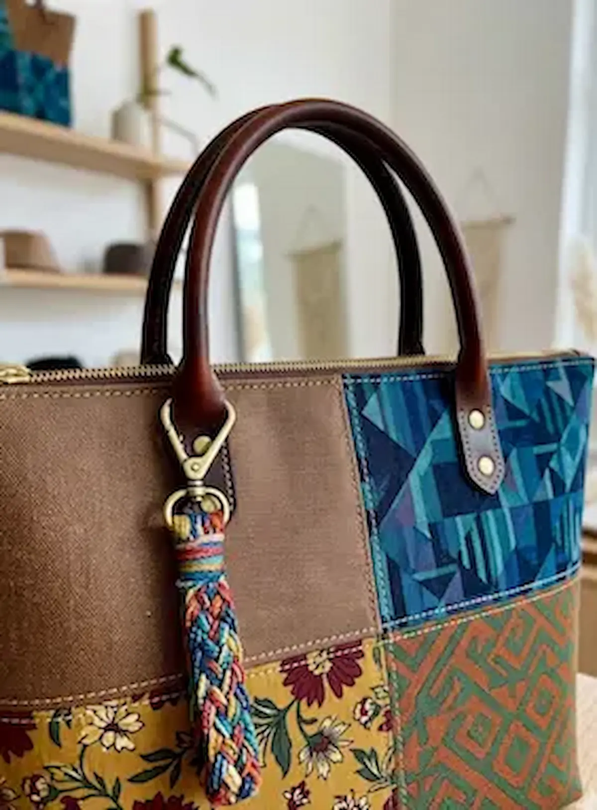 Detailansicht einer handgefertigten Tasche aus beschichtetem Canvas im Patchwork-Design mit Ethno-Mustern, floralen Elementen in Senfgelb und Ledergriffen.