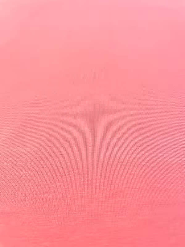 Nahaufnahme eines lachsfarbenen Baumwolljerseys mit feiner Maschenstruktur, 159 cm breit, ideal für Kinderkleidung und Damenmode.