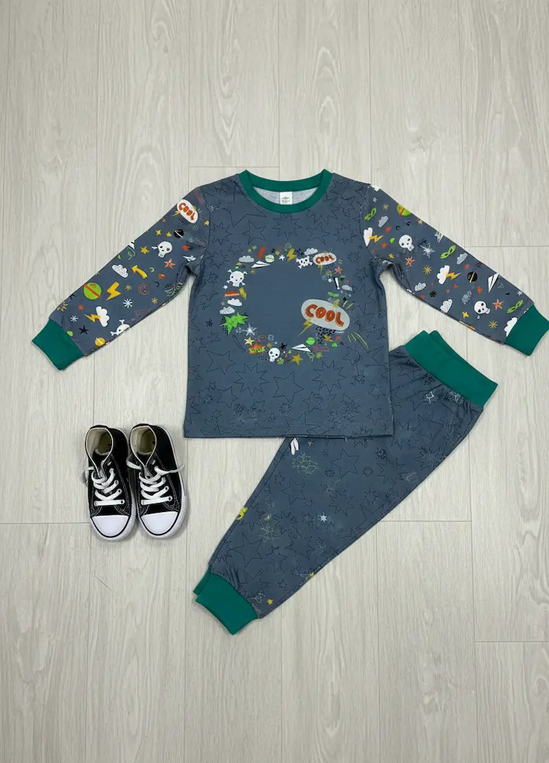Genähtes Designbeispiel aus unserem blaugrauen Jersey-Panel und dem passenden Kombistoff: Ein zweiteiliger Kinder-Schlafanzug bestehend aus einem langärmligen Shirt mit dem runden Comic-Kranz-Motiv auf der Brust, Ärmeln im passenden Comic-Streumuster und