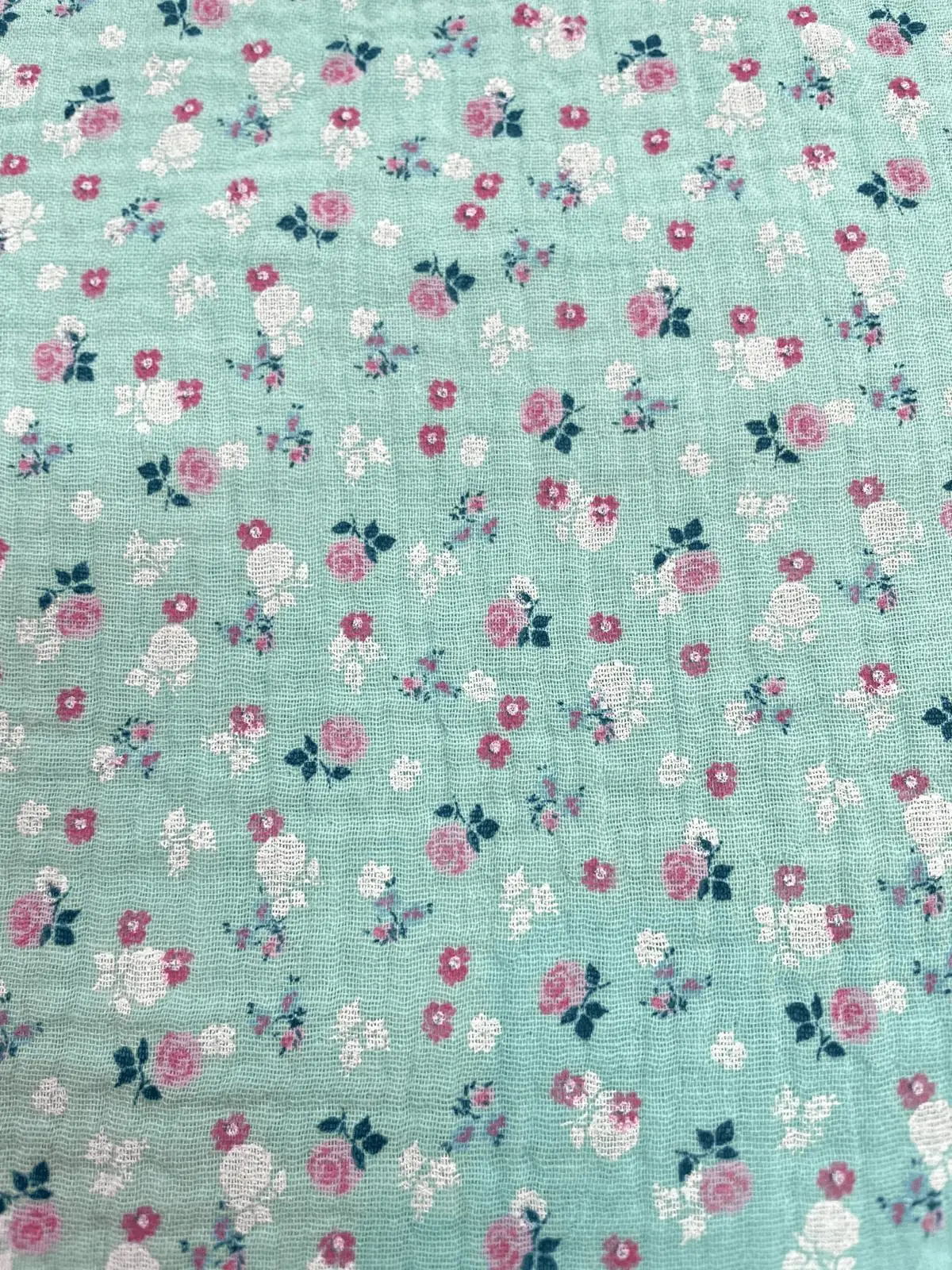 Mintgrüner Musselin-Stoff mit romantischem Blumenmuster aus rosa Rosen und weißen Blüten. Hochwertige Double-Gauze Meterware aus Baumwolle mit feiner Crinkle-Struktur im Vintage-Stil