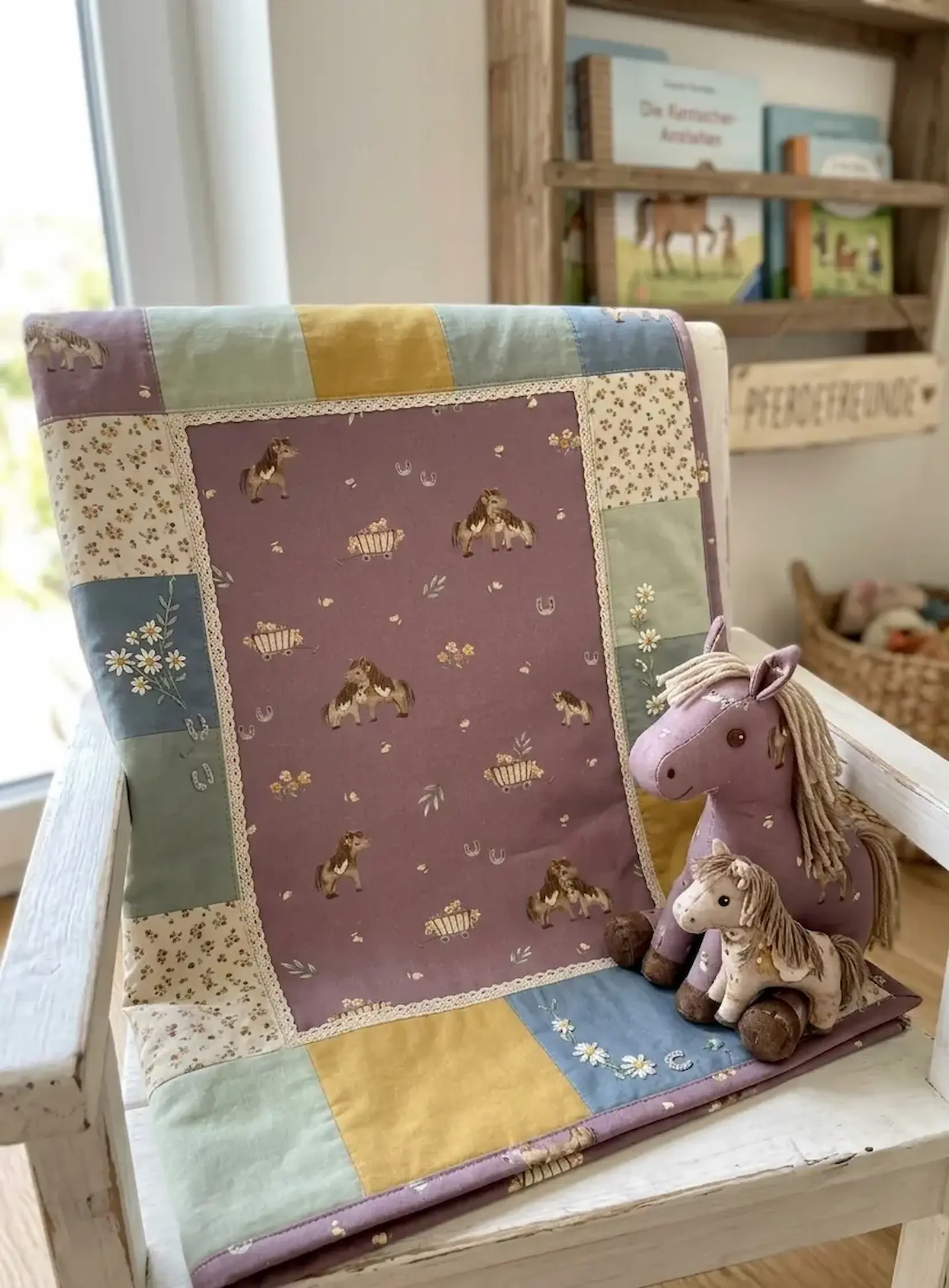 Patchwork-Kinderdecke aus Baumwollstoff mit Pferdemotiven in Mauve, kombiniert mit Senfgelb und Salbeigrün, dazu passende Stoff-Pferde.