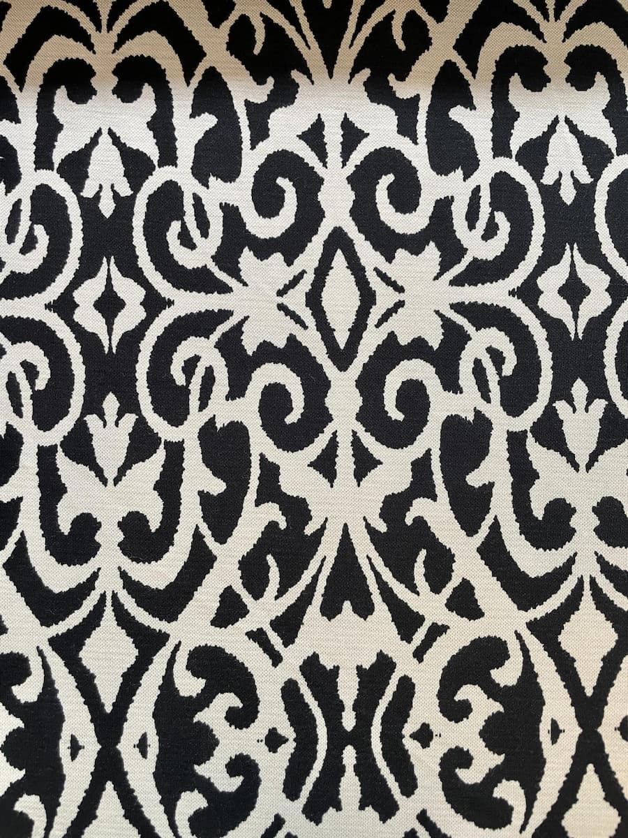 Nahaufnahme eines schwarz-weißen Viskose-Mix Stoffes mit großem Ornament-Muster und kontrastierendem Nadelstreifen-Design.