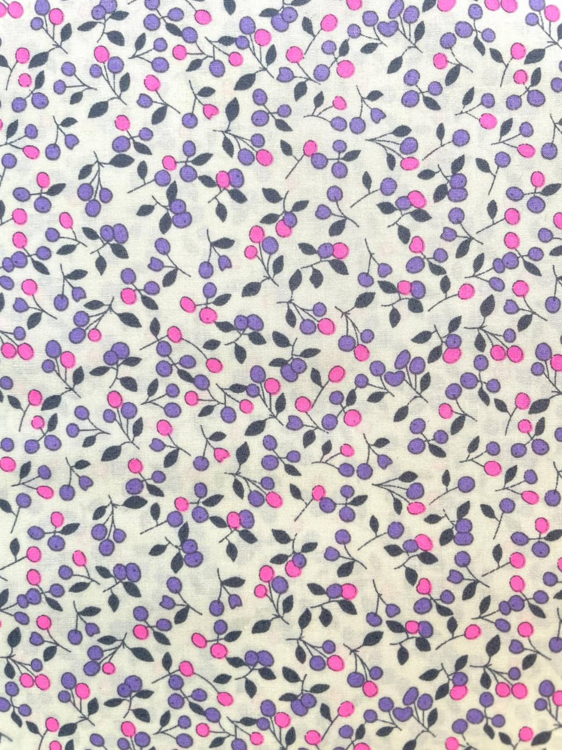 Zertifizierte Bio-Baumwolle Webware mit ökologischem Beeren-Druck in Lila und Pink auf naturweißem Hintergrund..