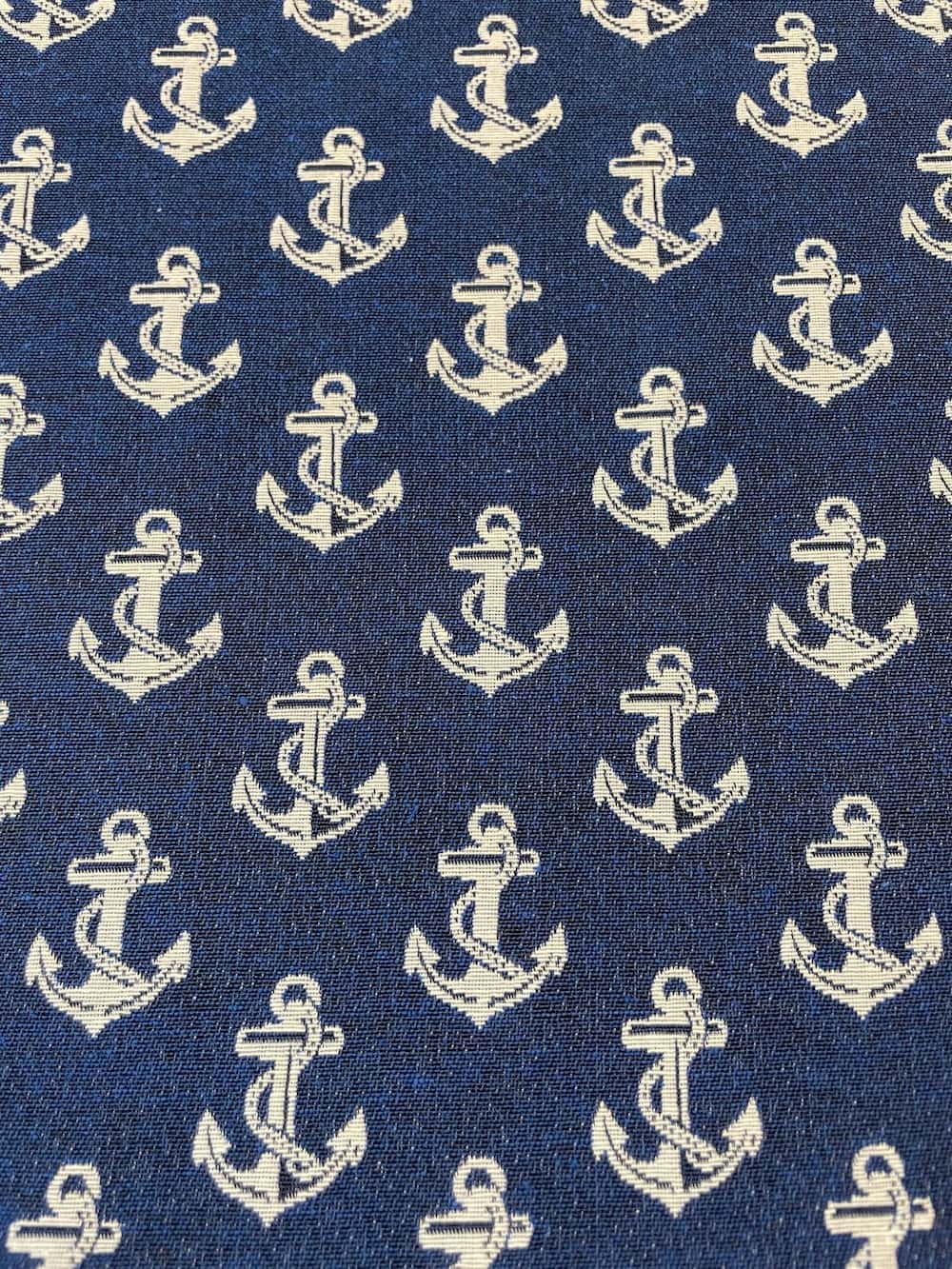 Gewebter Deko-Gobelinstoff als Meterware mit hellen, eingewebten Ankern auf einem kräftigen dunkelblauen Jacquard-Hintergrund.