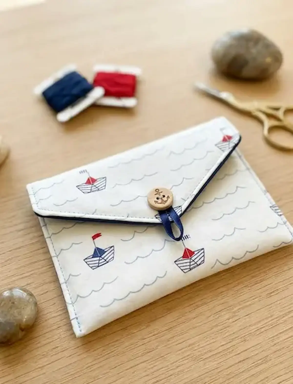 Selbstgenähte Tasche aus maritime Baumwollstoff mit Papierschiff-Muster, Anker-Knopf und blauer Gummischlaufe