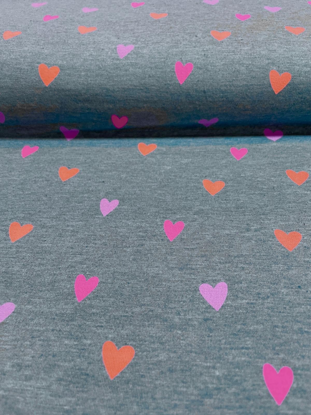 Grau melierter Jersey-Stoff bedruckt mit kleinen Herzen in leuchtendem Neon-Pink, Koralle und Orange.