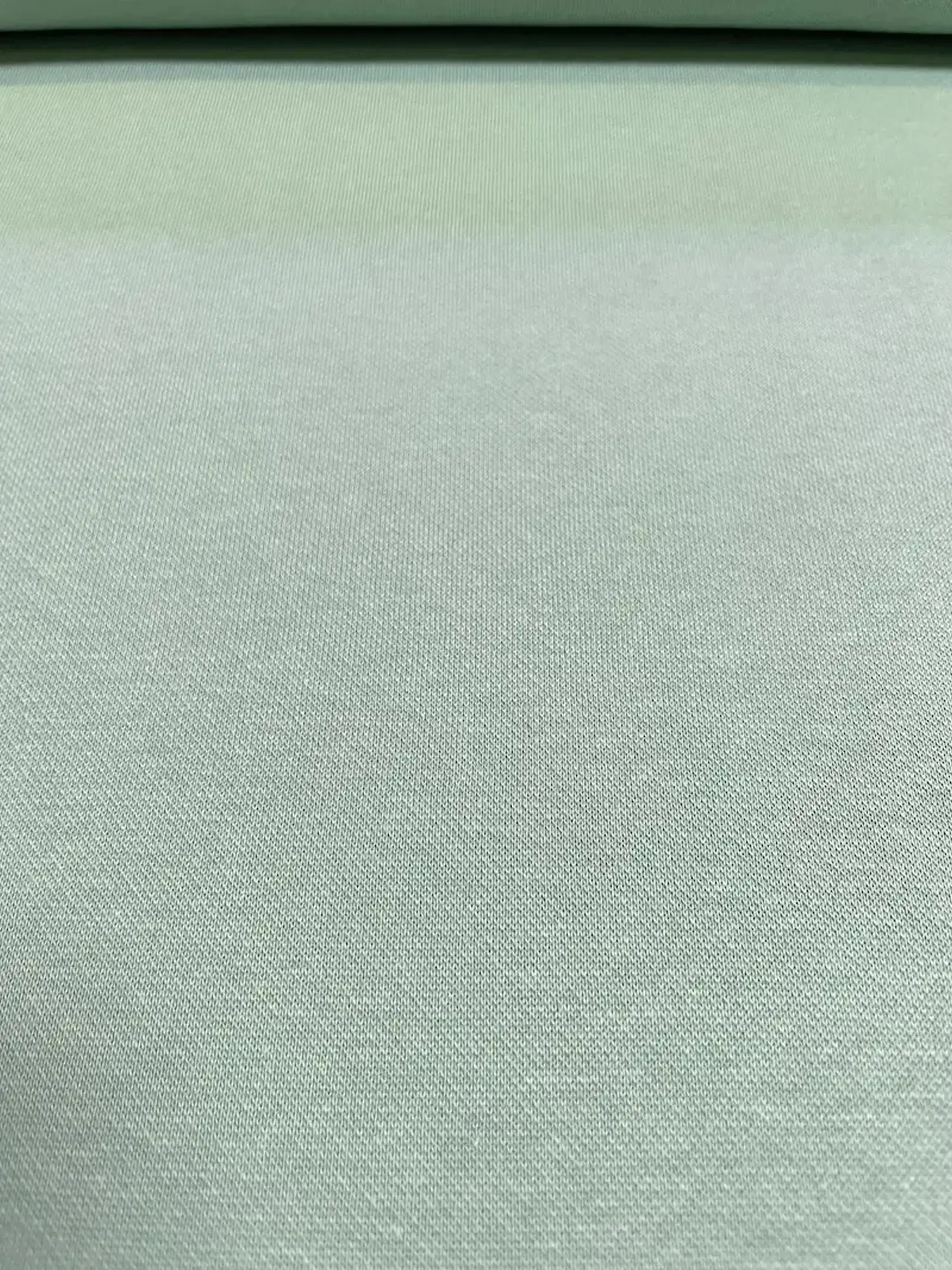 Unifarber Strick-Jacquard Stoff als Meterware in mattem Salbeigrün mit feiner, charakteristischer Strickstruktur, ideal für gemütliche Kleidung und Cardigans.