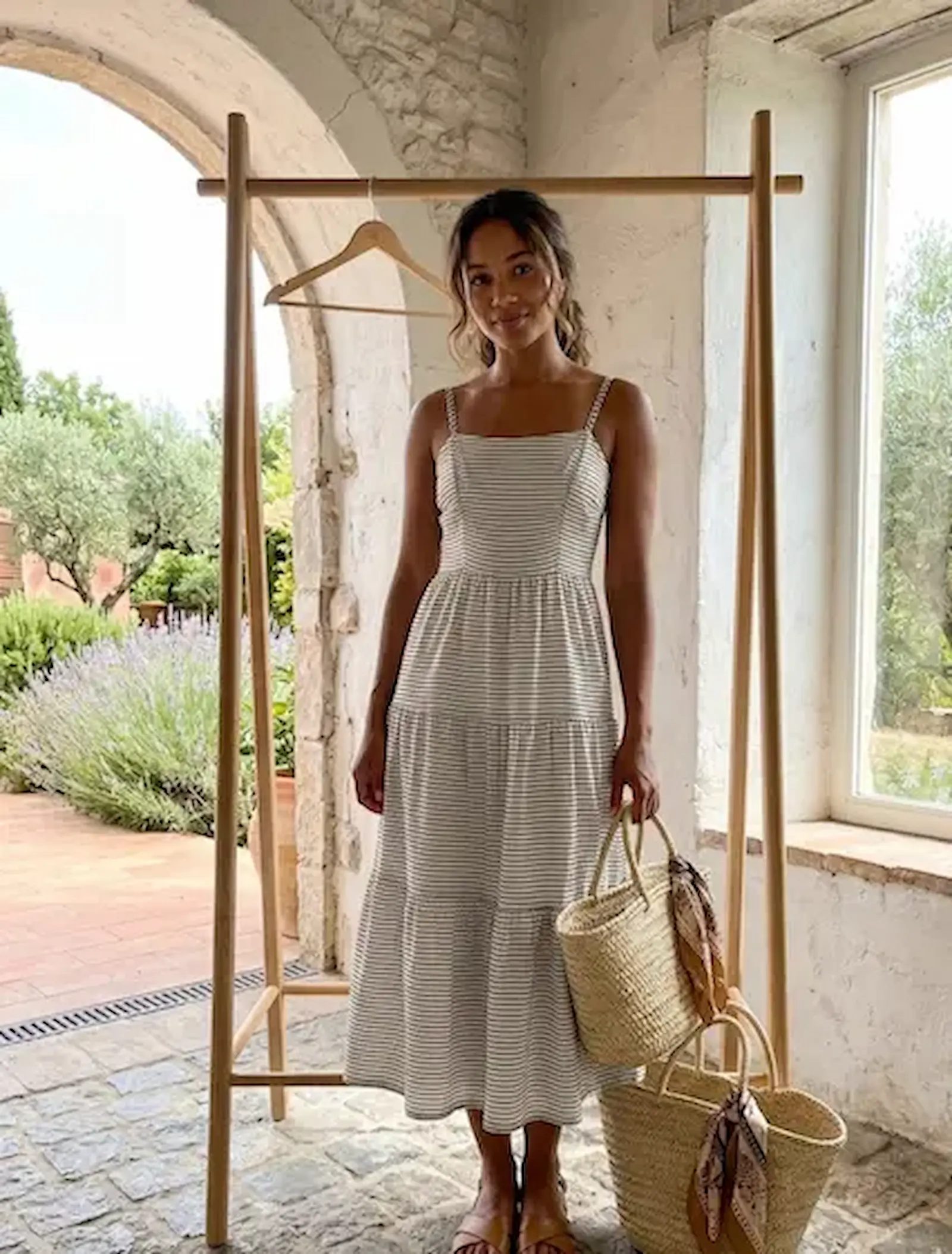 Detailansicht eines gestuften Maxikleids aus fein gestreiftem Jersey-Stoff in Beige und Braun, getragen in einem mediterranen Ambiente.