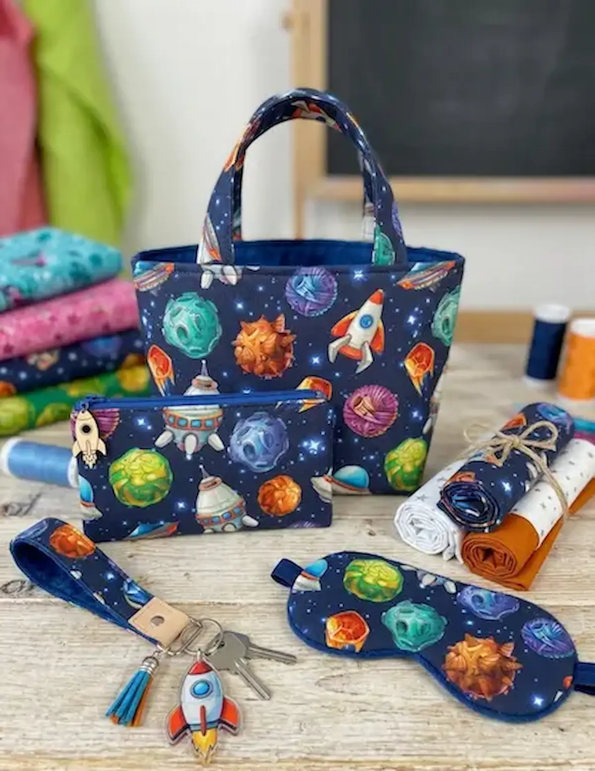 Nähset aus dunkelblauer Baumwoll-Webware mit Weltraum-Motiven wie Raketen und Planeten: Kleine Tasche, Etui, Schlafmaske und Schlüsselband