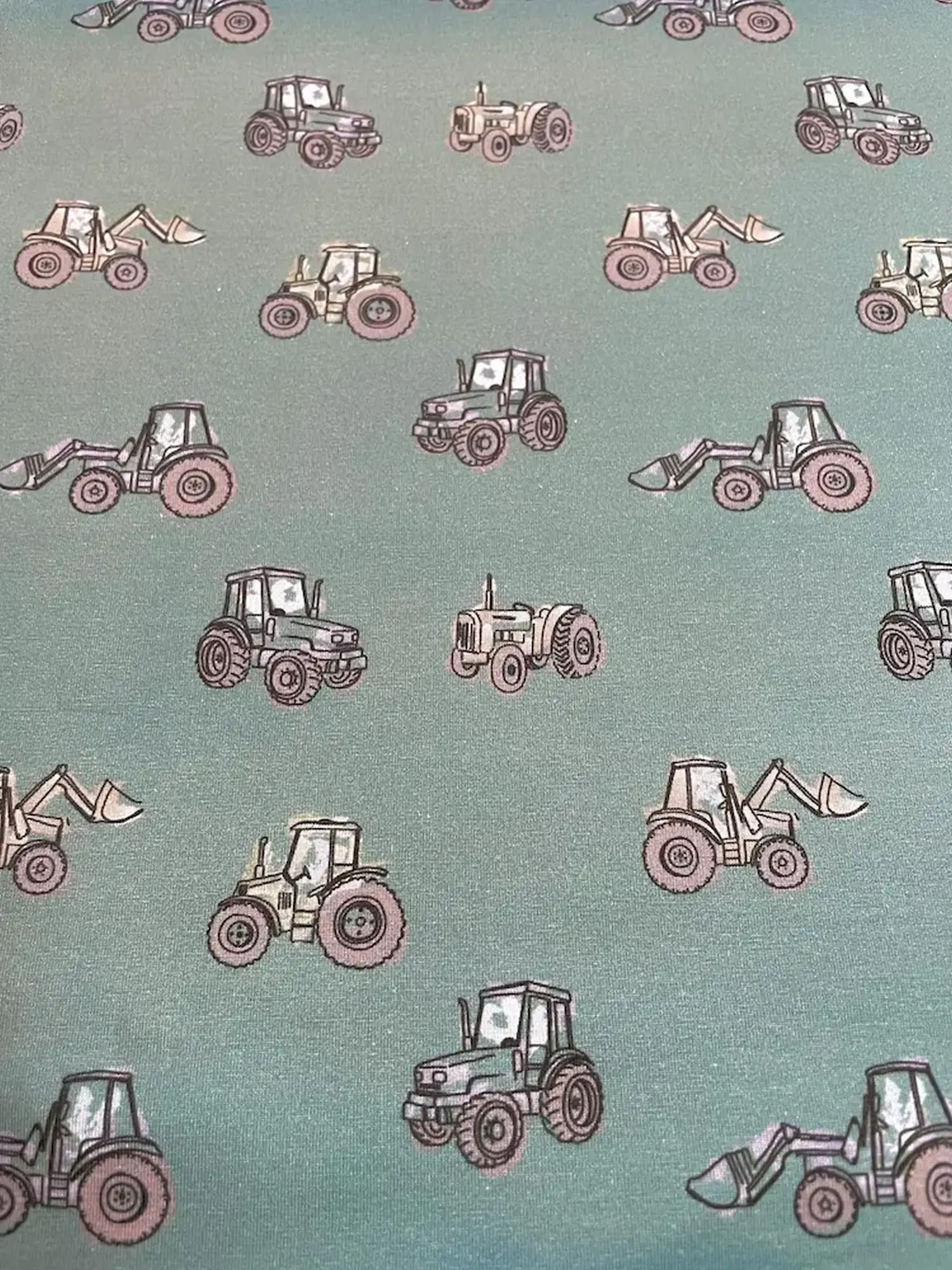 Salbeigrüner Jerseystoff als Meterware, bedruckt mit verschiedenen gezeichneten Traktoren, Baggern und landwirtschaftlichen Fahrzeugen im Vintage-Stil.