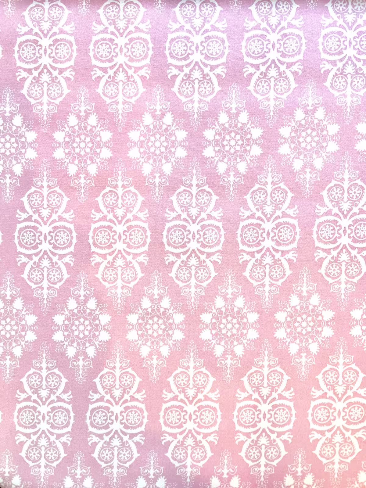 hell-rosa farbener Baumwoll-Stretch-Stoff als Meterware, bedruckt mit einem eleganten, weißen Damast-Muster, drapiert für Wohn-Deko-Projekte.