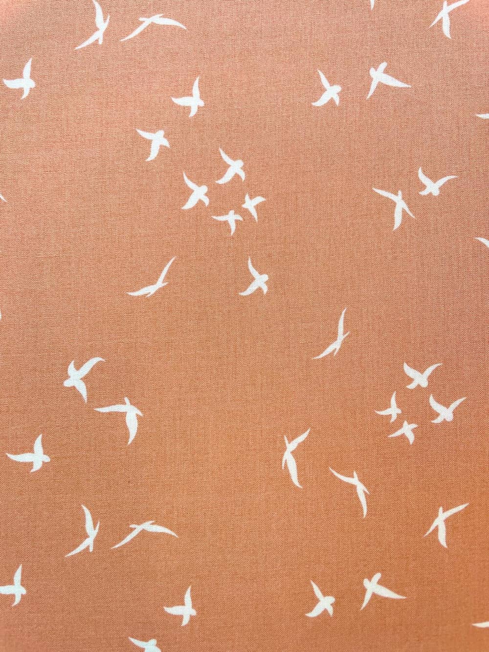 Weich fließender Viskose-Webstoff in Terrakotta mit weißem Vogel-Print; Meterware für sommerliche Bekleidung.