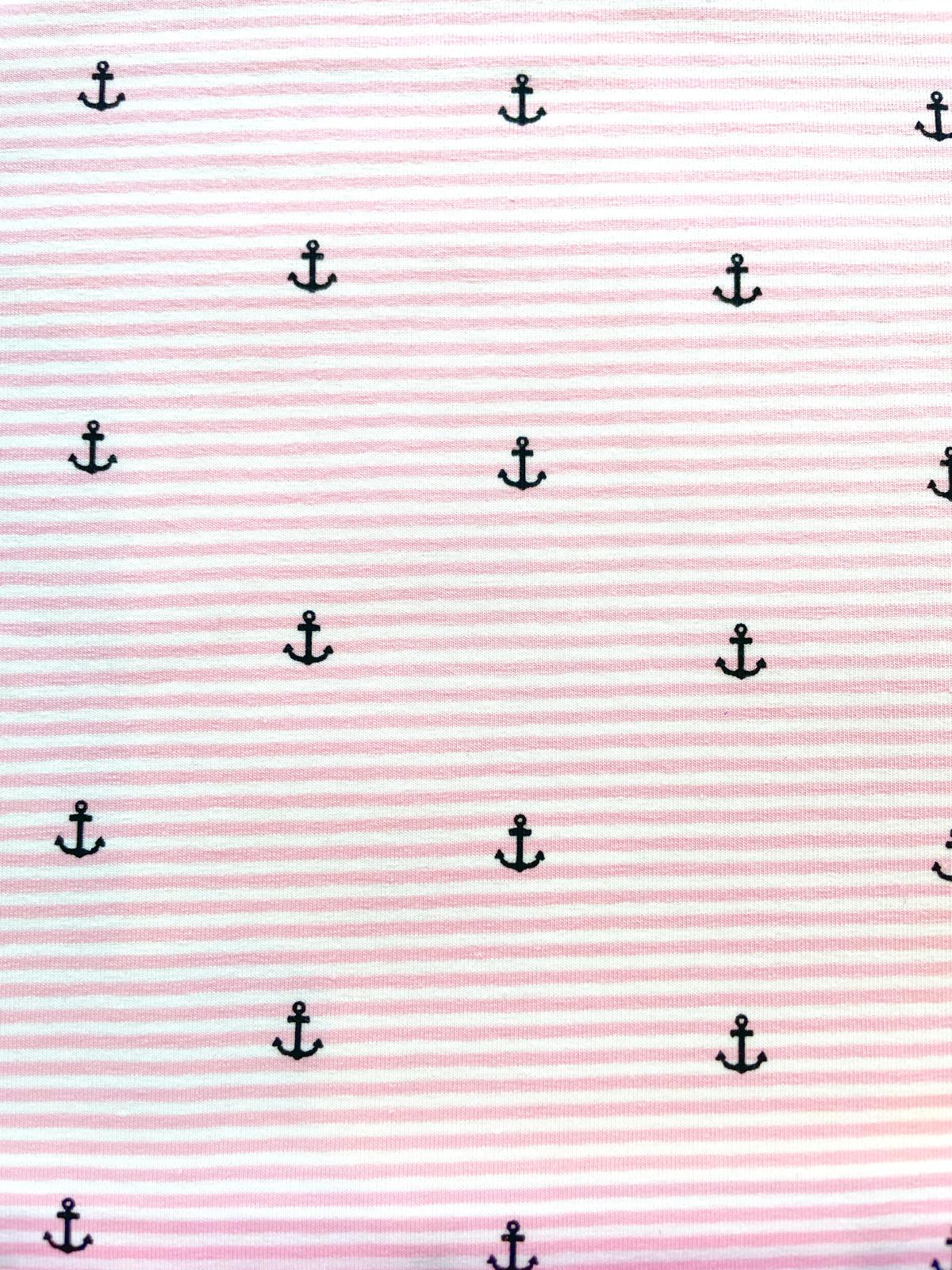 Nahaufnahme von elastischem Baumwolljersey in Rosa und Weiß gestreift, bedruckt mit kleinen dunkelblauen Ankern; hochwertige maritime Meterware für Kinderkleidung, sommerliche Kleider und Accessoires.