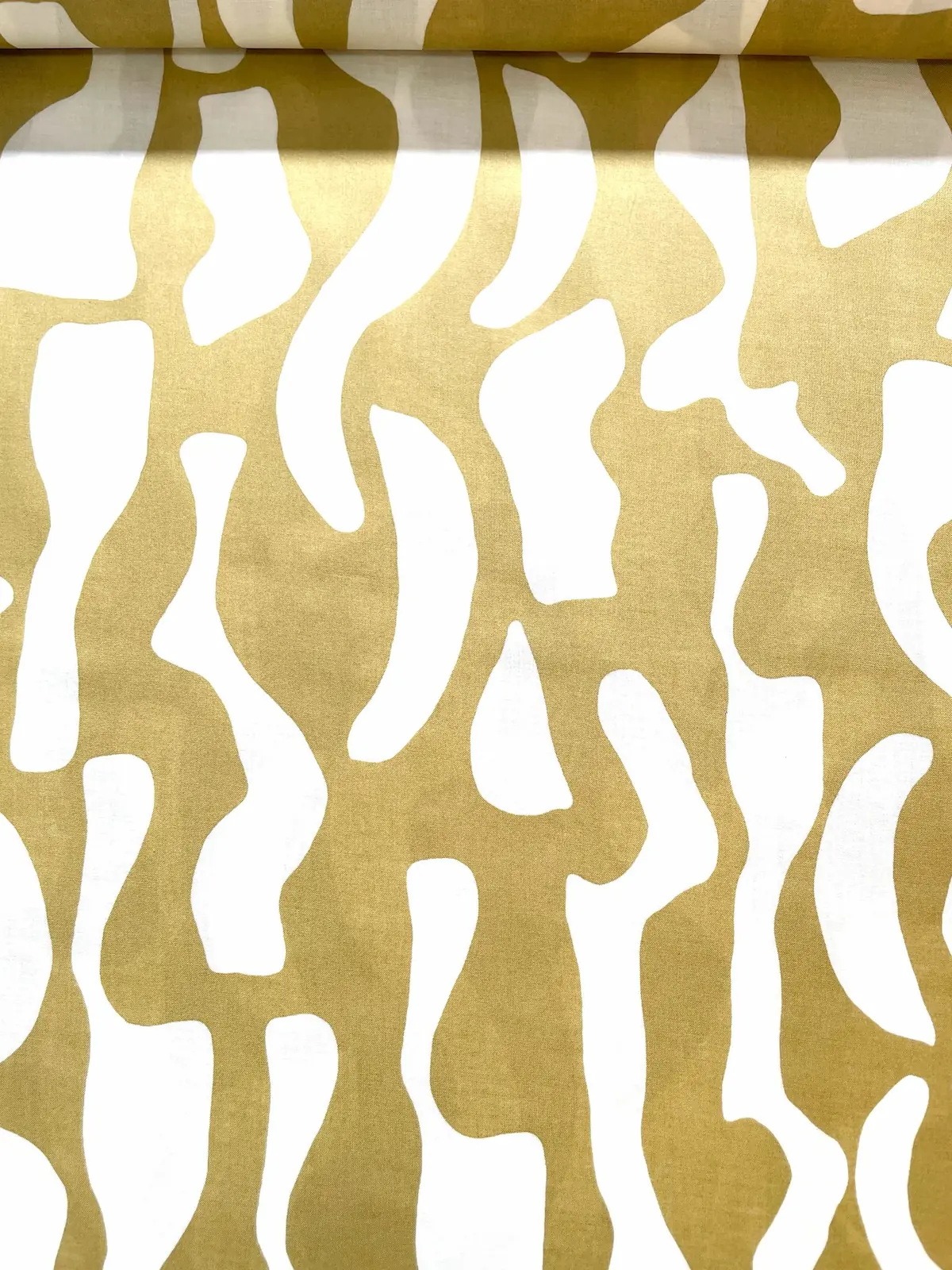 Eine flächige Nahaufnahme von leichtem Baumwoll-Voile als Meterware, bedruckt mit einem modernen, abstrakten Wellenmuster in leuchtendem Gelbgrün auf einem weißen Untergrund.