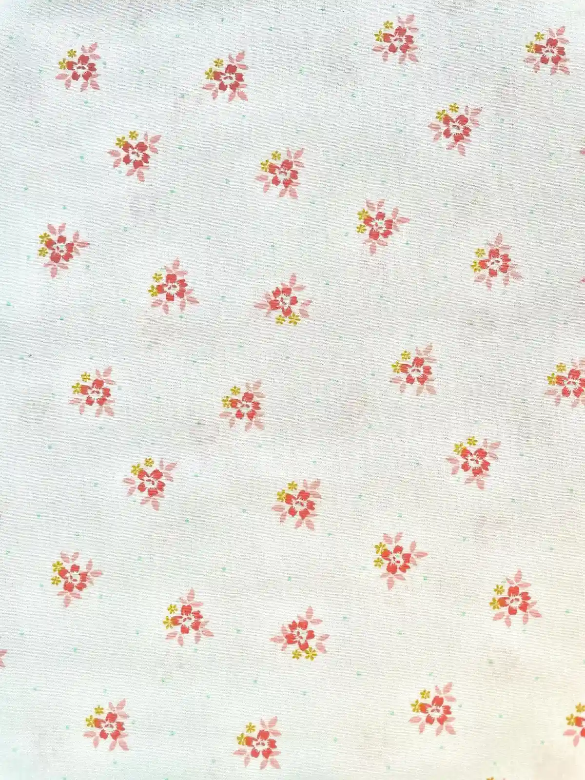 Weißer Baumwoll-Popeline Stoff mit kleinen, fein verteilten rosa und korallfarbenen Blüten, glattes Gewebe für leichte Sommerkleider und Kinderkleidung.