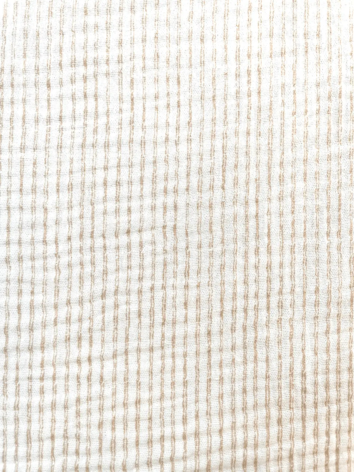 Nahaufnahme eines cremefarbenen Musselinstoffs aus 100% Baumwolle mit feinen, vertikal verlaufenden Streifen in Beige. Die charakteristische, luftige Double-Gauze-Struktur ist deutlich erkennbar.