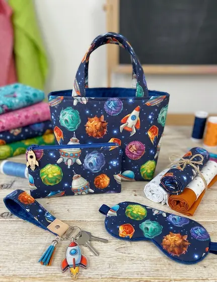 Nähset aus dunkelblauer Baumwoll-Webware mit Weltraum-Motiven wie Raketen und Planeten: Kleine Tasche, Etui, Schlafmaske und Schlüsselband