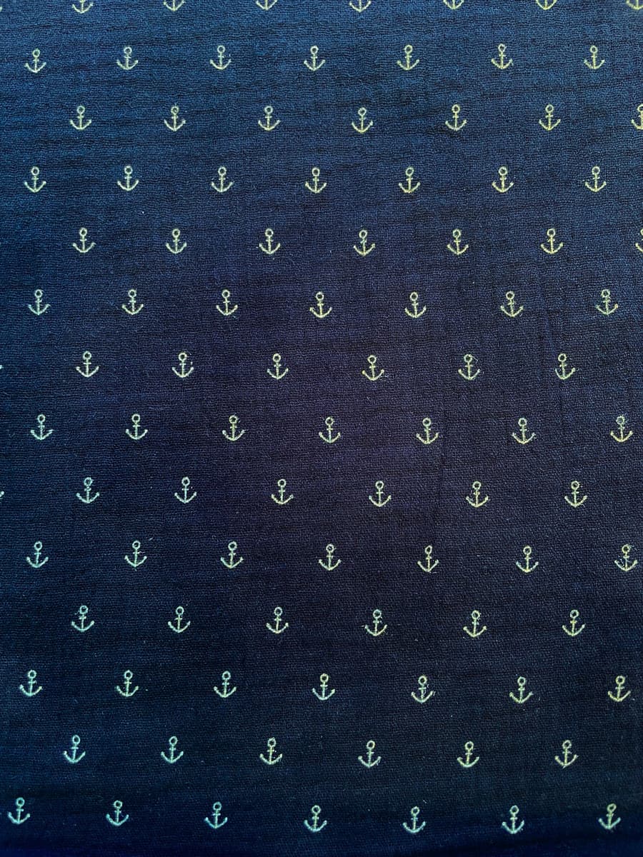 Dunkelblauer Musselin-Stoff aus Baumwolle mit kleinen, hellen Anker-Motiven als Meterware, ideal für maritime Babykleidung und Accessoires