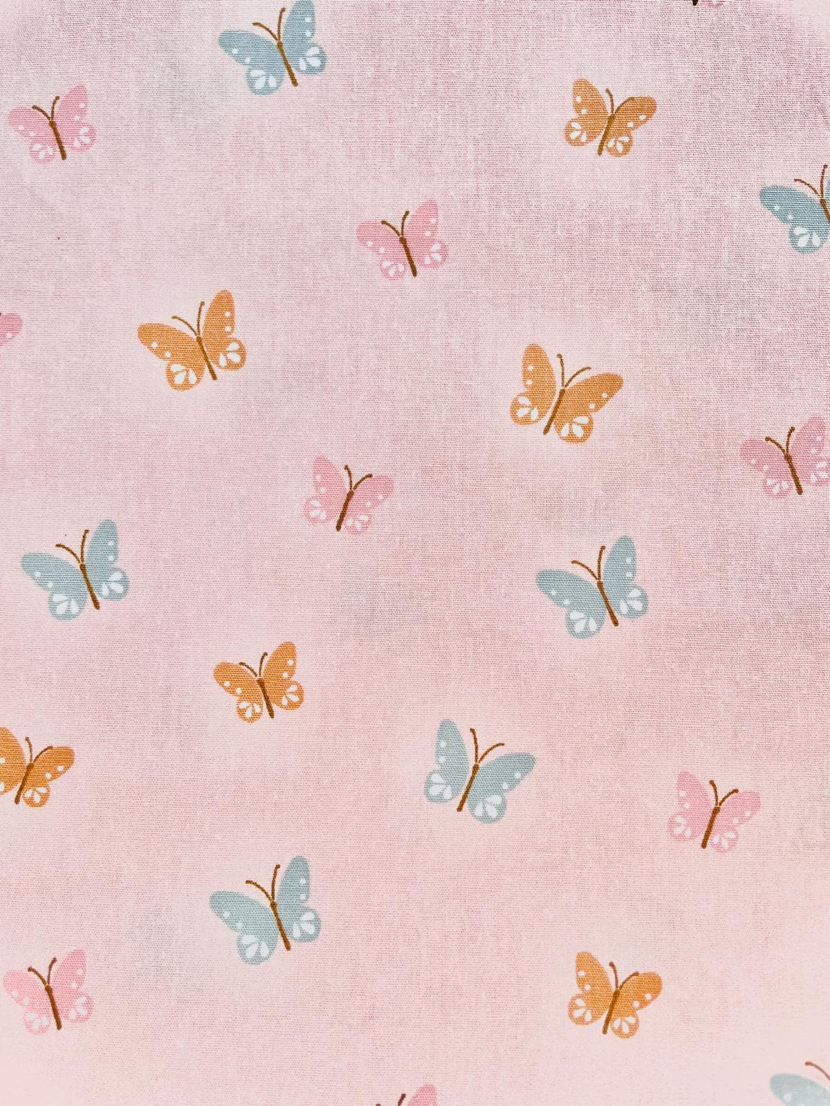 Zarter Bio-Baumwollstoff in Pastellrosa bedruckt mit bunten Schmetterlingen; leichte Popeline-Webware für Schultüten und Kinderkleidung.