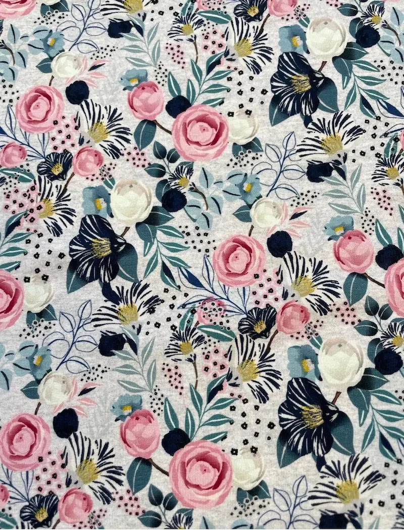 Elastischer Jersey-Stoff mit modernem Blumenmuster. Das Design zeigt große rosa Rosen und dunkelblaue Blüten kombiniert mit feinen Blättern auf einem hellgrau melierten Untergrund. Hochwertiger Druck für Damen- und Kinderbekleidung.