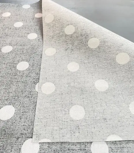 Drapierte beschichtete Baumwolle in grauer Leinen-Optik mit weißen Punkten, zeigt die matte Beschichtung und die helle Stoffrückseite.