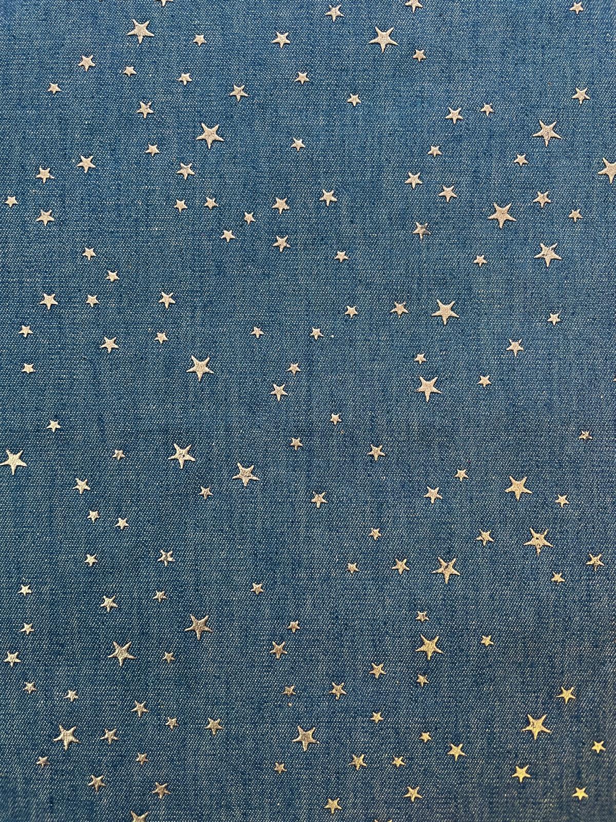 Nahaufnahme von jeansblauem Baumwollstoff mit fest aufgebrachten, silbernen Metall-Sternen. Die Sterne sind matt-glänzend ohne Glitzer, ideal für Kinderhosen und Schultüten.