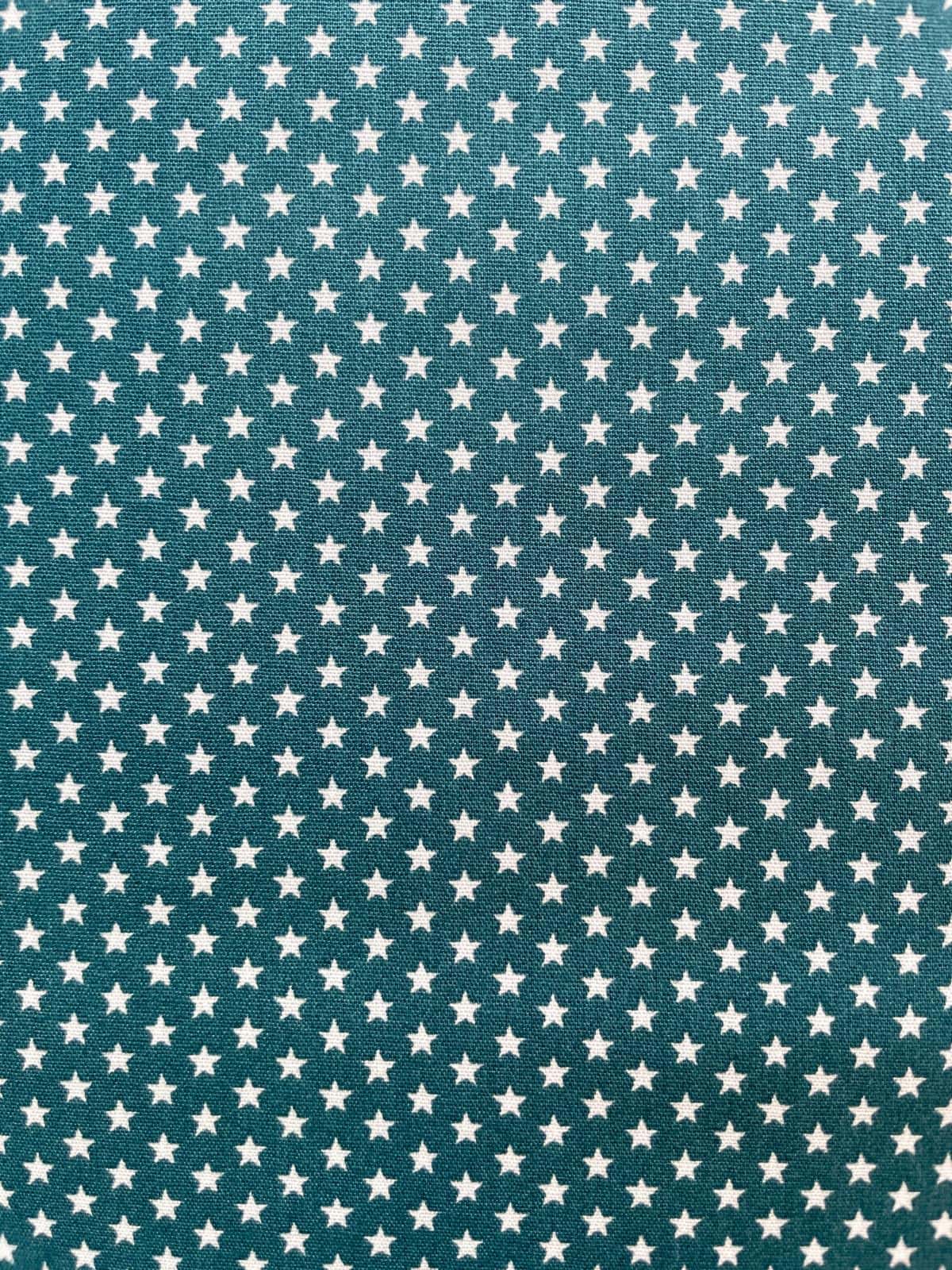 Hochwertiger Baumwoll-Webware-Meterwarestoff in tiefem Petrol (147 cm breit, 130 g/m²) mit einem feinen weißen Sternenmuster, perfekt für Heimtextilien und DIY-Projekte.
