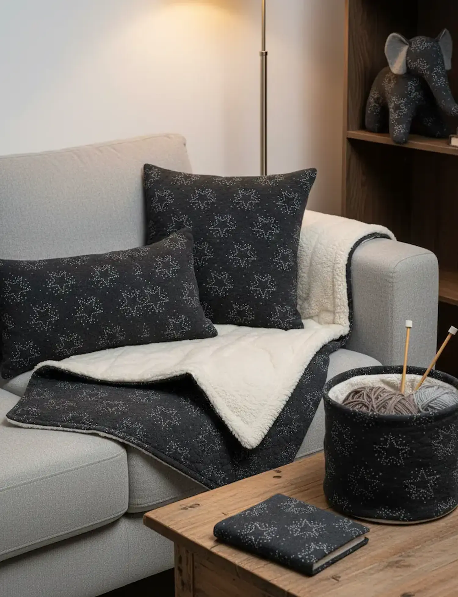 Gemütliches Sofa mit selbstgenähten Kissen, einer Kuscheldecke mit Teddyfutter und einem Utensilo aus dunkelgrauem Sweat-Steppstoff mit Sternenmuster.