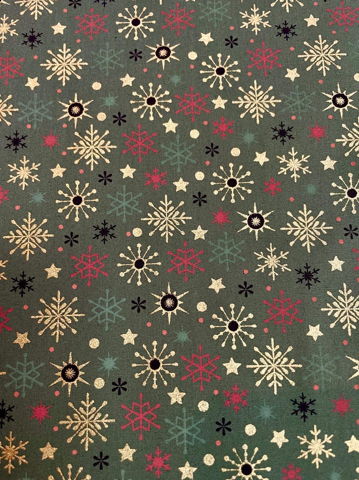 Festlicher Baumwollstoff als Meterware mit bunten Schneeflocken, Eiskristallen und Sternen in Gold, Rot, Schwarz und Hellgrün auf dunklem Tannengrün.