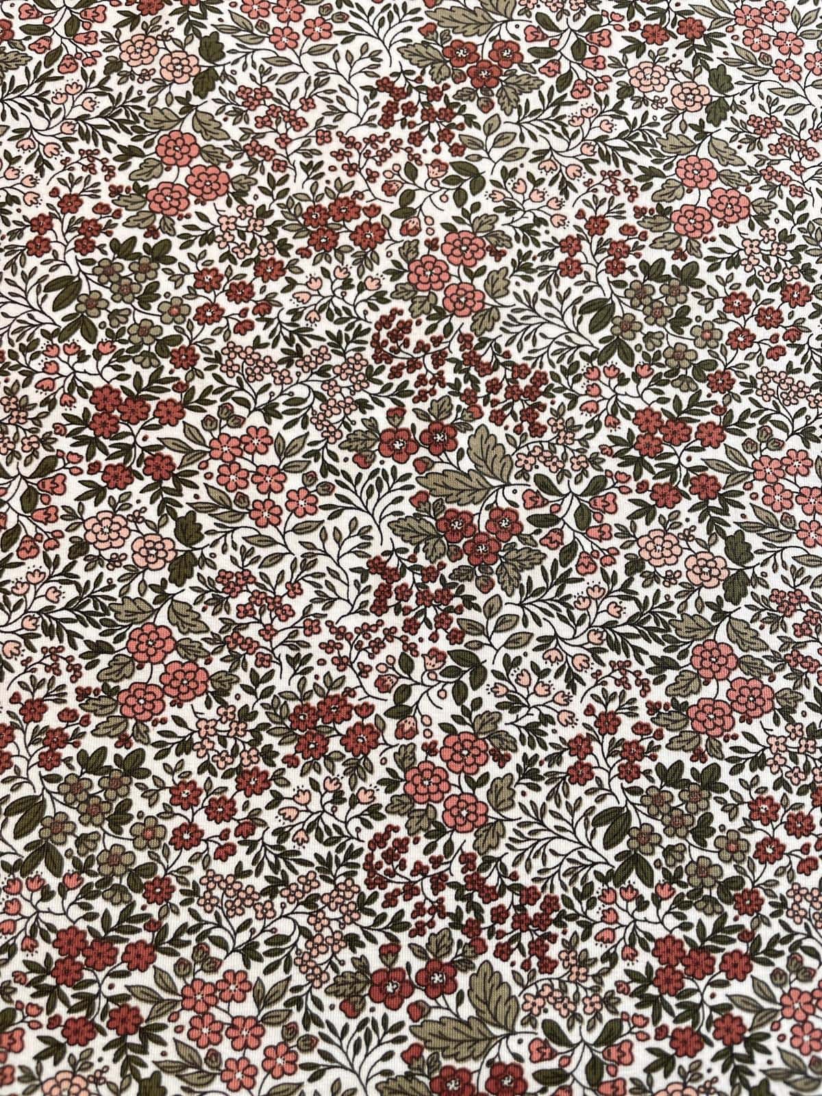 Elastischer Baumwolljersey Meterware mit filigranem Blumen-Muster in Altrosa, Rot und Grün auf hellem Grund bei stoffpfau.de.