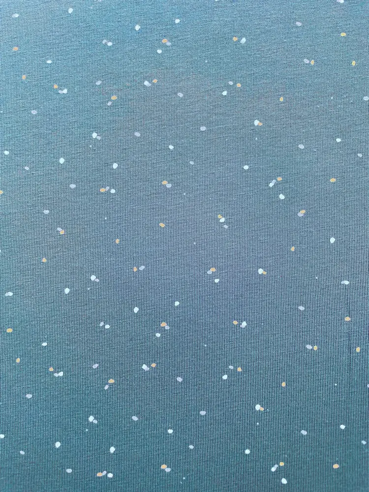 Nahaufnahme eines blaugrauen Jerseystoffs mit kleinen weißen und goldgelben Sprenkeln, Meterware für Bekleidung.