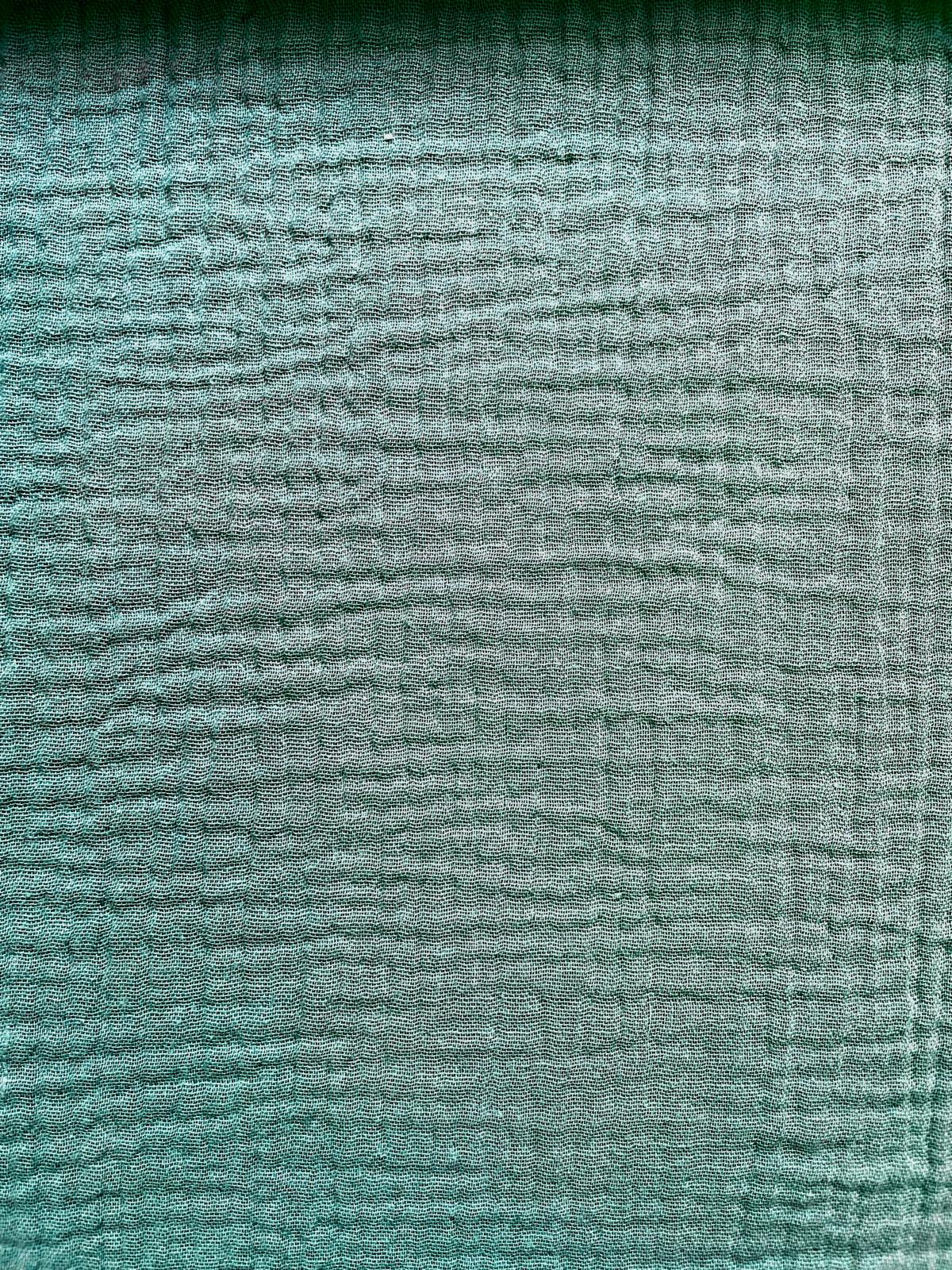 Nahaufnahme von salbeigrüner Musselin-Meterware aus 100% Baumwolle mit charakteristischer Crinkle-Struktur und weicher Weboptik.