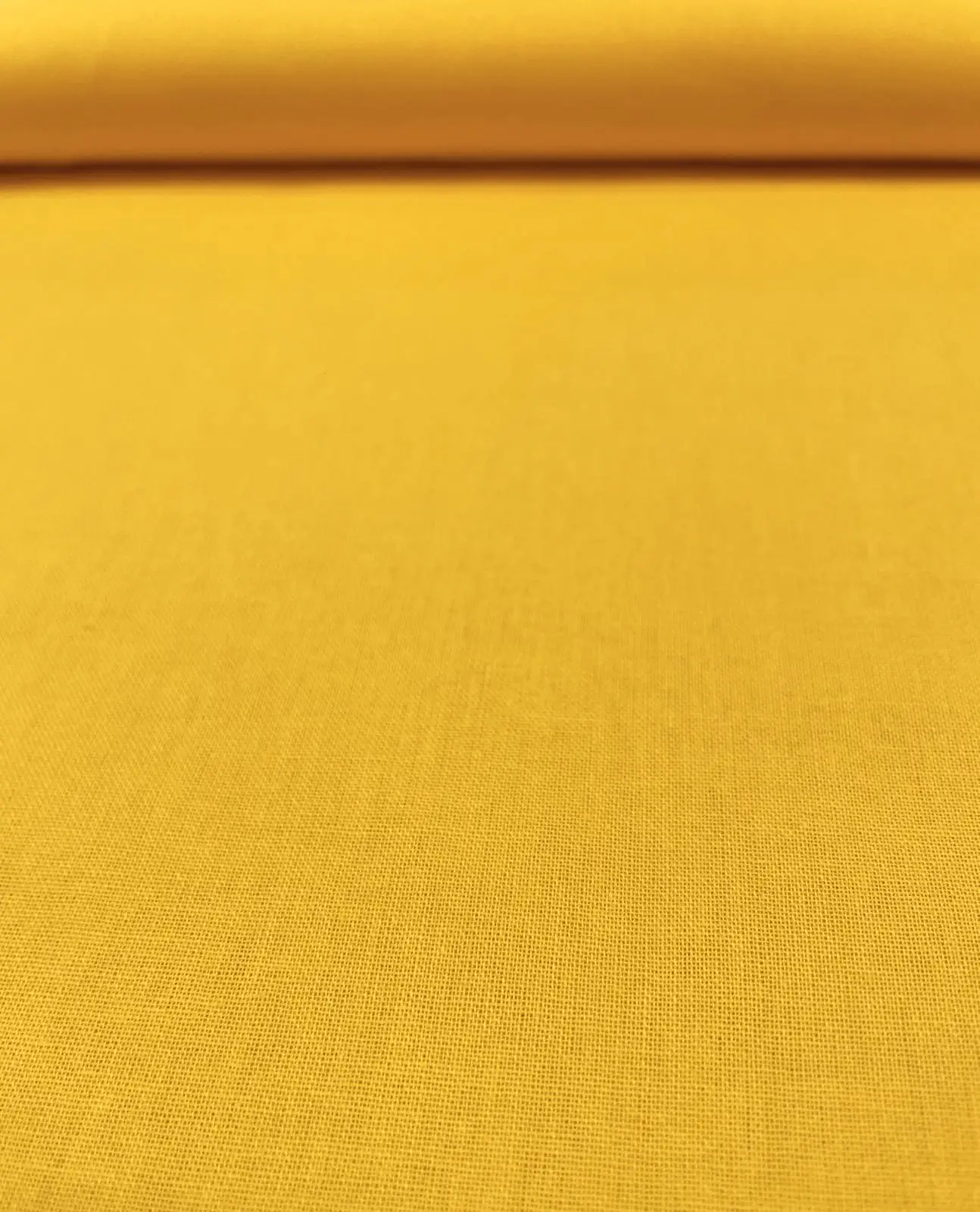 Farbenfrohe Raumdekoration im skandinavischen Stil mit handgemachten Wohnaccessoires aus unifarbenem, sonnengelbem Baumwollstoff, bestehend aus einem großen Stoffkorb auf dem Holzboden, Sternenkissen und runden Dekokissen mit weißer Pompon-Borte.