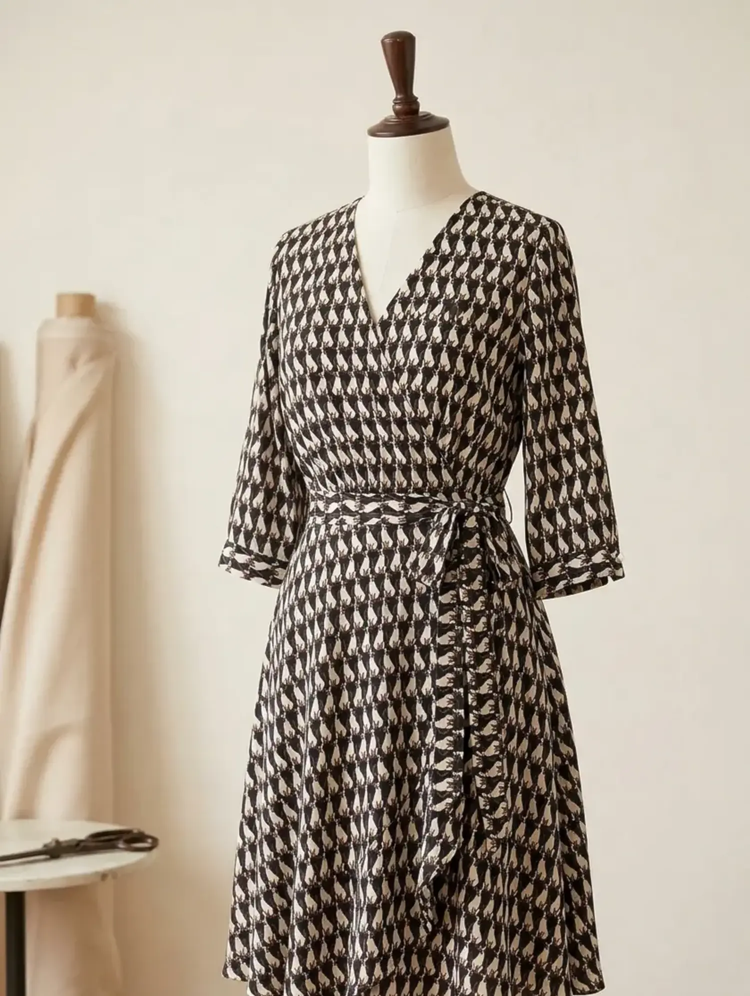 Elegantes Wickelkleid aus fließendem Viskose-Stoff mit modernem Katzen-Print in Schwarz und Beige auf einer Schneiderpuppe.