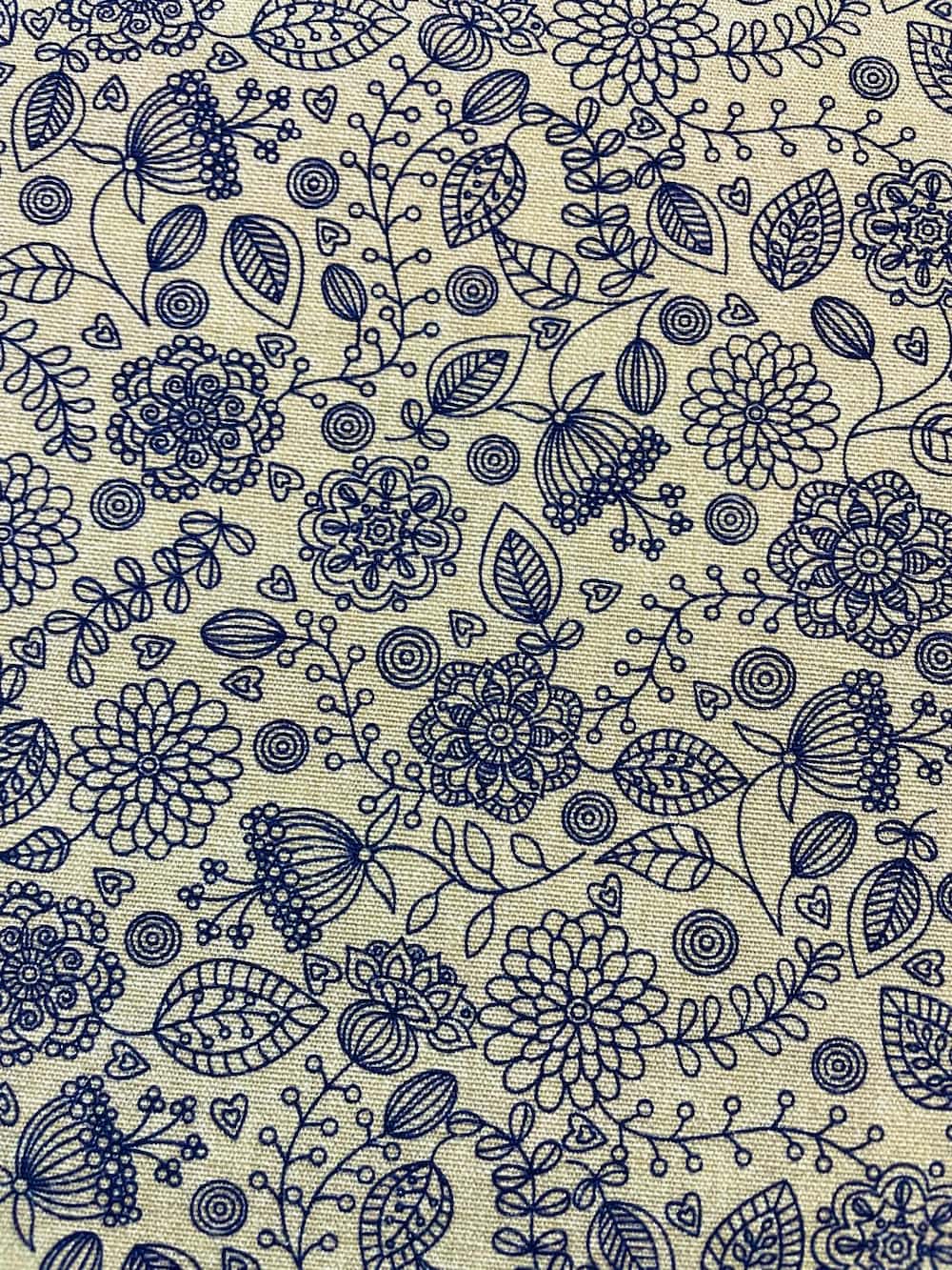 Strukturierter Canvas Dekostoff als Meterware in Natur-Beige mit einem feinen, dunkelblauen Linienmuster aus Blumen, Ranken und kleinen Herzen.