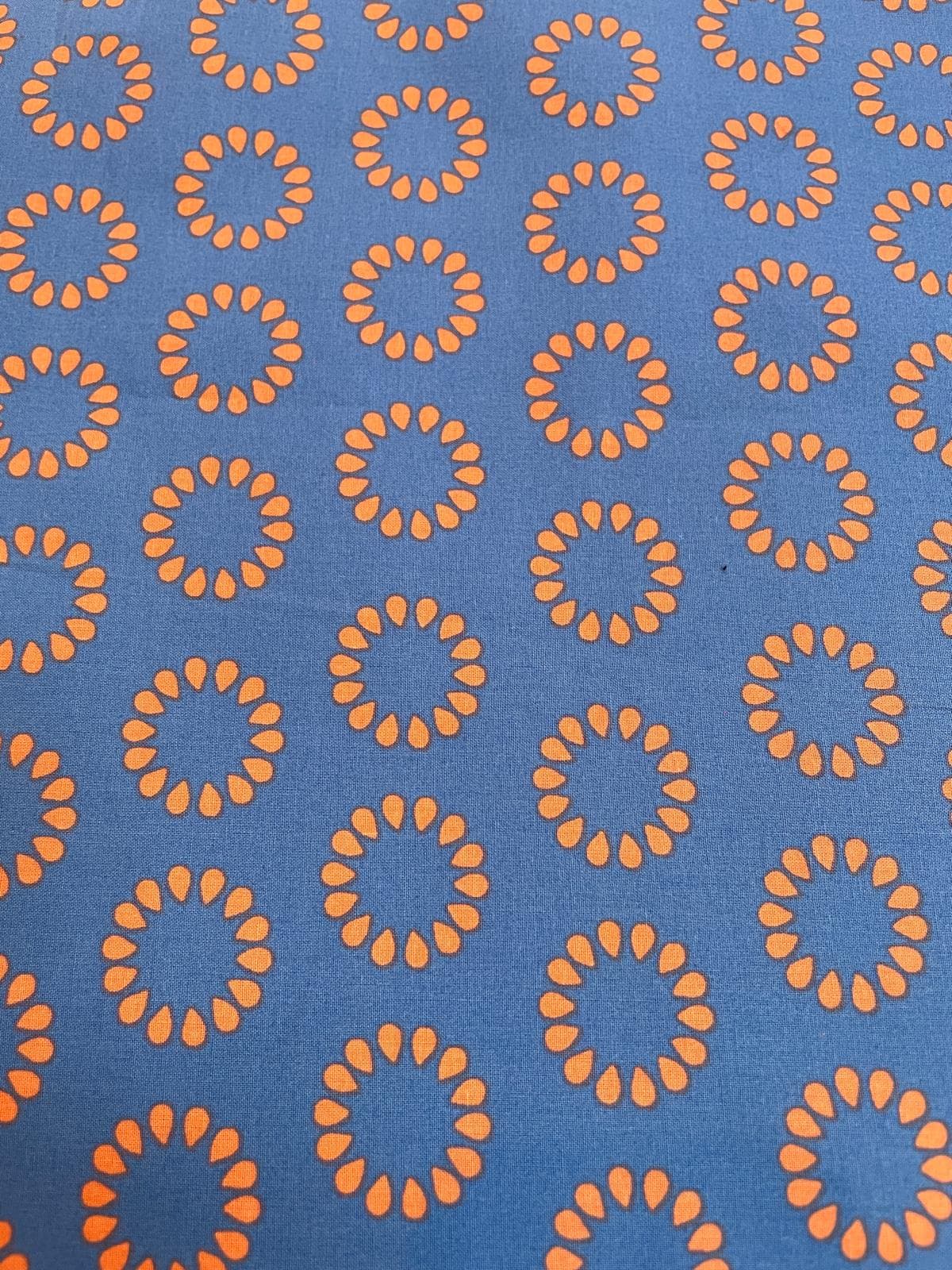 Beschichtete Baumwolle in Blau mit grafischem Retro-Muster aus orangefarbenen Kreisen – wasserabweisend.