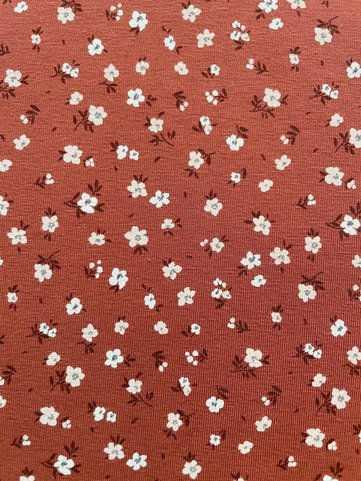 Weicher Jerseystoff in Rostbraun mit zierlichem weißen Blumenmuster, ideal für Kinderkleidung und Damenmode